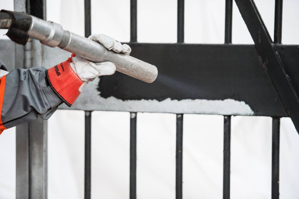 Een man is een hek aan het stralen met Sponge-Jet SpongeMedia